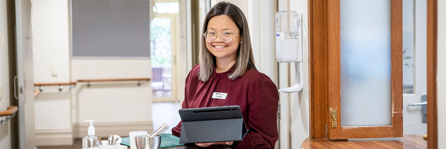 Young lady in corporate attire and with glasses smiling in office environment